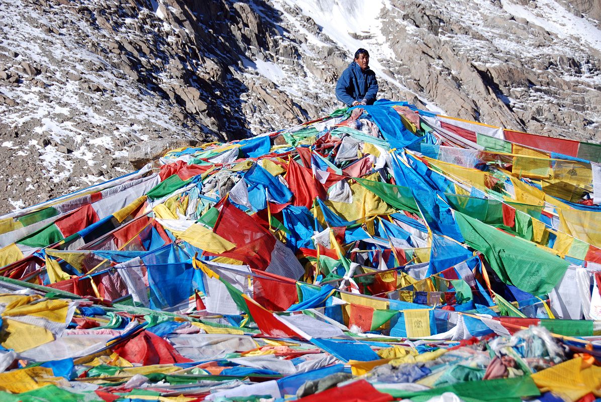 54 Tashi Connects Prayer Flags To Top Of Dolma Do Rock On Mount Kailash Outer Kora Only the shape of the large Dolma Do, Rock of Dolma (Tara), that Tibetans call Phawang Mebar is visible beneath all the prayer flags. My local guide Tashi connects his prayer flags to the rock.